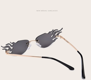 Macro view of rimless flame-shaped sunglasses with dark gray lenses and gold metal temples