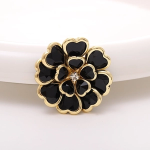 Macro view of a retro black and gold acrylic flower charm with a central crystal stone