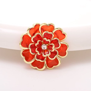 Macro detail of red acrylic camellia with gold edges and central crystal rhinestone