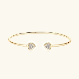 Dettaglio di un bracciale aperto dorato con due cuori e cristalli di zircone micro-pavé