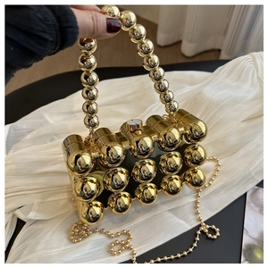 Detail einer goldenen Abendtasche aus Metallkugeln mit Perlenkordel und Kettengurt