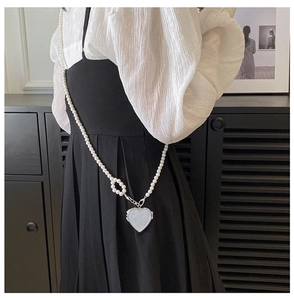 Detail of a chic heart-shaped mini bag with white faux pearl chain strap on model