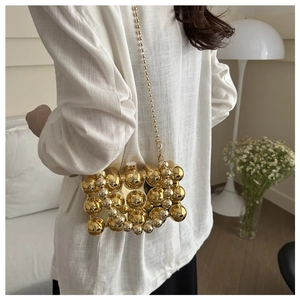 Detail einer großen goldenen Abendtasche mit Kettenriemen am Modell getragen