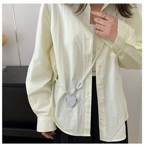 Detail of elegant pearl crossbody body chain featuring a silver heart-shaped pendant