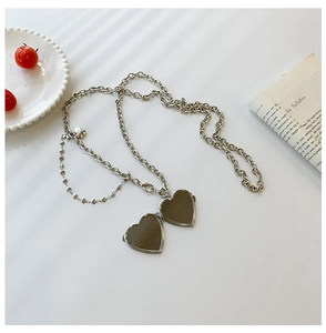 Close-up of open heart locket pendant with double layer silver chain on vintage book