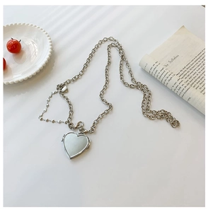 Detail of silver heart-shaped locket pendant on an asymmetric chain with macro view