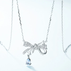 S925 sterling silver bow necklace with sparkling crystals and light blue teardrop topaz pendant
