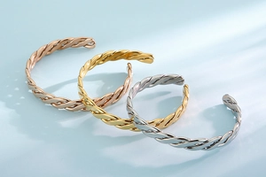 Detail of twisted cable open cuff bracelets in rose gold, yellow gold, and silver finishes