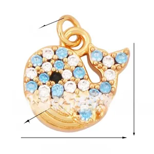 Vue détaillée d'un petit pendentif baleine en laiton doré avec des zircons bleus et blancs