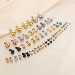Minimalist round stud earrings set in various sizes and metallic colors on silk background