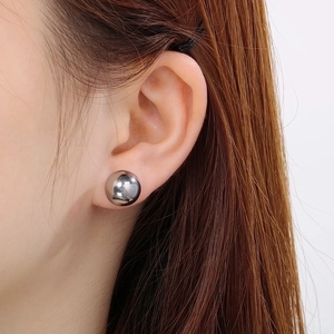 Minimalist silver stainless steel ball stud earrings shown on an ear for a modern look