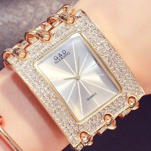 Close-up of gold square quartz watch with triple chain strap and sparkling rhinestones