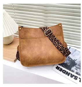 Detail of vintage brown leather tote with trendy leopard print wide shoulder strap