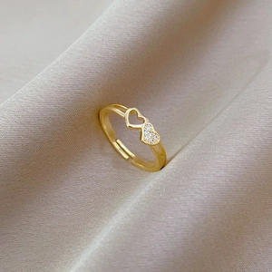 Adjustable gold ring with double heart design and sparkling white crystals on silk