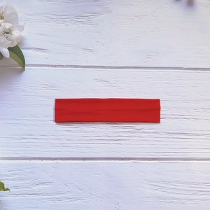 Detailed view of red elastic knit yoga headband texture on white wooden background