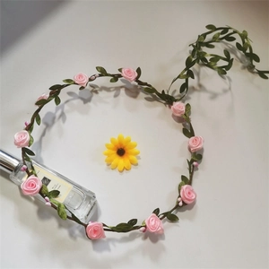 Detail of pink faux rose floral crown with green leaves and vine headband design