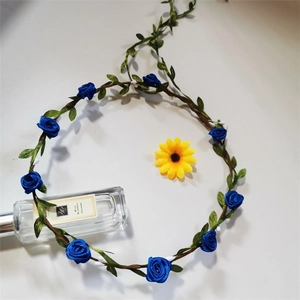 Detail of blue fabric roses and green leaves on a brown vine floral headband