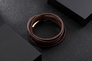 Detail of brown braided leather multi-layer bracelet with gold metal buckle