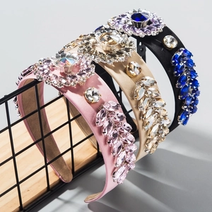 Tre cerchietti imbottiti con cristalli in rosa, beige e nero su un supporto di metallo