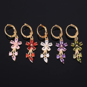 Macro shot of colorful floral zircon drop earrings with gold base on reflective background