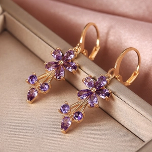 Elegant gold-plated flower earrings with purple zircons and tassels on silk background