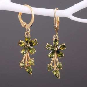Macro shot of gold flower drop earrings with olive green cubic zirconia and leverback