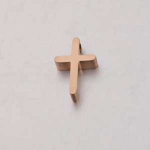 Polished golden stainless steel cross pendant on a minimalist light marble background