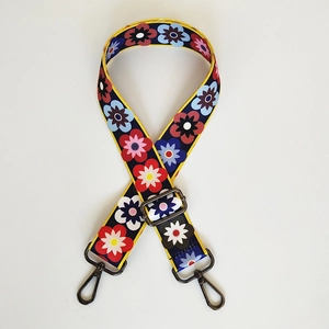 Dettaglio della tracolla per borsa a fiori con motivi colorati e ganci in metallo