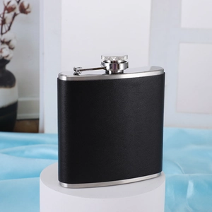 Close-up of a 6oz stainless steel hip flask with black leather wrap on a display stand