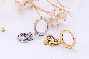 Macro shot of gold and silver frog hoop earrings with multicolored pavé zircon stones