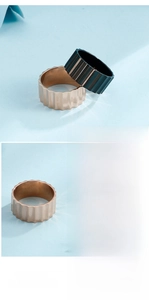 Detailed view of wide metal rings with vertical ribbed texture in gold and green