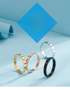 Close-up of four geometric gear rings in gold, silver, black and rose gold finishes