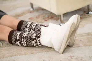 Detailed knit texture of reindeer and snowflake patterns on winter thermal leg warmers