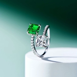 Toi et Moi ring featuring square emerald-cut green and clear stones on a silver band