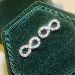 Elegant silver infinity symbol stud earrings with shimmering cubic zirconia on velvet box