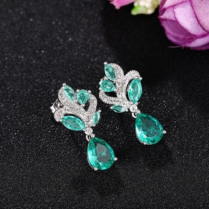 Elegant emerald drop earrings with marquise green gems and crystals on black background