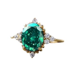 Elegant gold ring featuring a large oval green gemstone with small crystal accents
