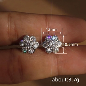 Elegant silver flower stud earrings with sparkling zircon crystals shown on fingers