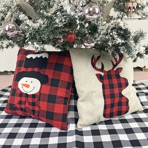 Christmas plaid pillow covers with snowman and reindeer designs under the tree