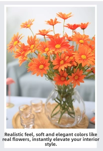 Close-up of realistic orange daisy artificial flowers in a glass vase on a wooden tray