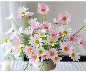 Close-up of artificial pink and white daisies in a woven vase for home decoration