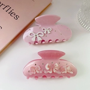Elegant pink bow hair clips with rhinestones shown on a minimalist white tabletop