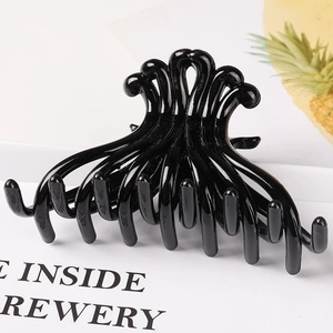 Detailed view of a large black octopus-style hair claw clip on a stylish magazine