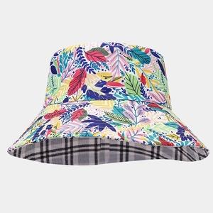 Detail of wide brim sun hat showing vibrant leaf print and black and white check pattern