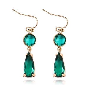 Detail of drop-shaped gold earrings with green K9 crystal pendants and faceted glass