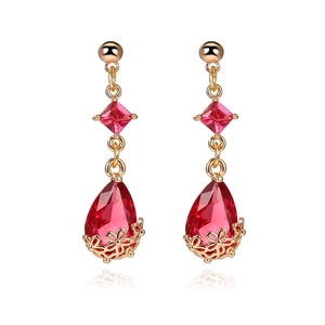 Detail view of 18K gold teardrop earrings featuring faceted red crystal and floral filigree