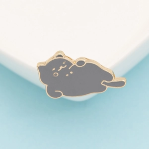 Detailed view of a cute grey enamel cat brooch with a gold-plated metal edge