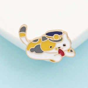 Close-up of a cute calico cat enamel pin wearing a blue conductor hat on a bicolour backdrop
