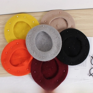 Flat lay of multi-colored pearl-embellished woolen berets for children on a wooden table