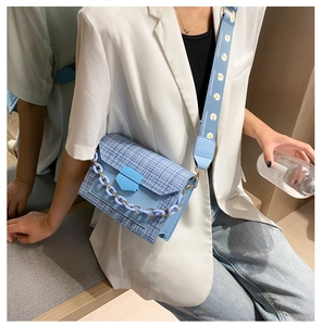 Detail of light blue tweed crossbody bag with resin chain and daisy embroidery strap